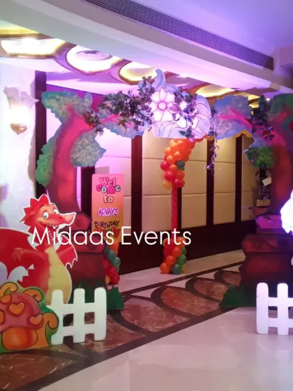 A grand entrance to the Jurassic world. This themed entrance arch for a dinosaur party features colorful balloons, custom tree props, and cute dinosaur cutouts to welcome the guests.