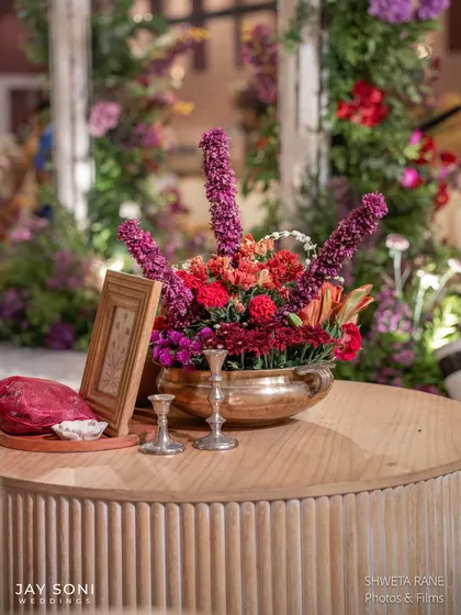 Another colorful centerpiece from the "Garden of Vows" wedding, with a mix of red, purple, and orange flowers in a brass bowl.