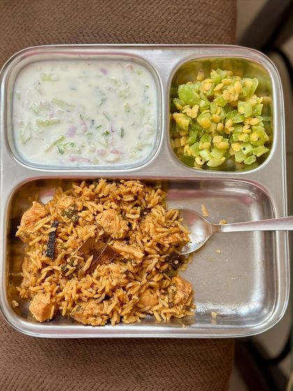 A delicious chicken biryani served with sautéed snake gourd and a cooling cucumber raita.