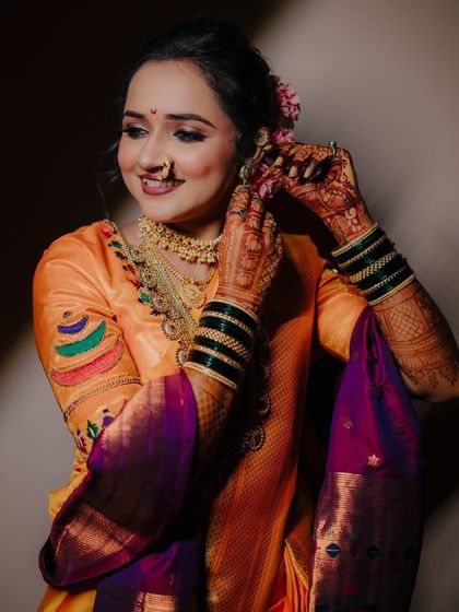 A candid getting-ready shot. The bride smiles as she puts on her earrings, a small but significant moment before the main ceremony.