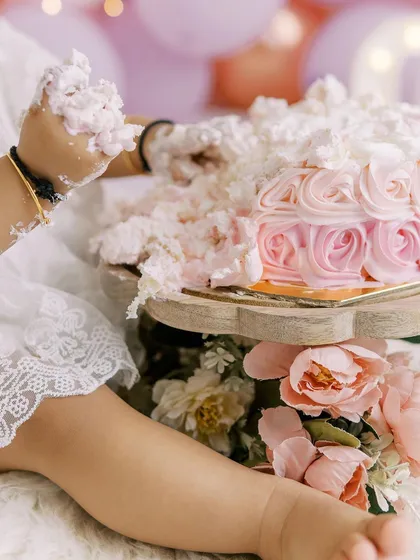 A close-up on the action. A tiny hand reaching into the beautifully decorated pink rosette cake, ready for the smash.