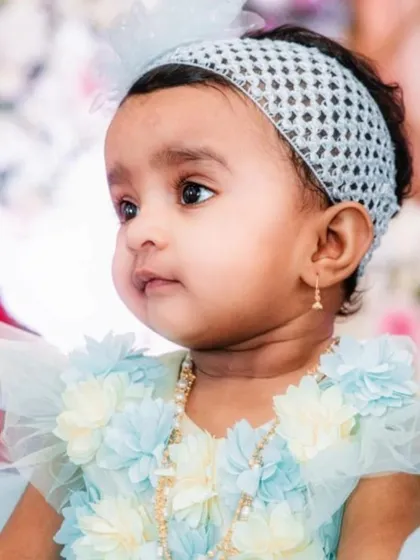 A candid portrait of the baby girl looking thoughtfully to the side during her naming ceremony celebrations.