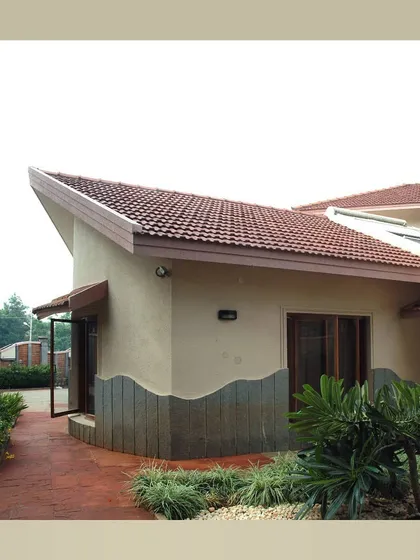 Another view of the house with the flowing roofline and stone wall base.