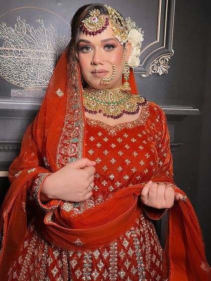 A closer look at the bodice and dupatta of the red-orange velvet bridal set. The sheer dupatta is edged with matching embroidery, balancing the richness of the velvet and completing the traditional look.