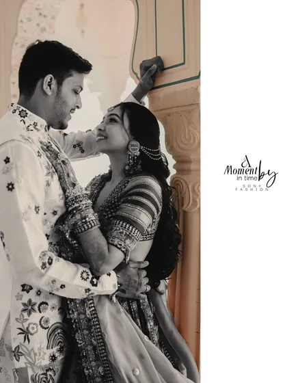 A sepia-toned intimate portrait of the couple in a palace corridor. The bride's adoring gaze upwards at her partner creates a deeply romantic and timeless feel.