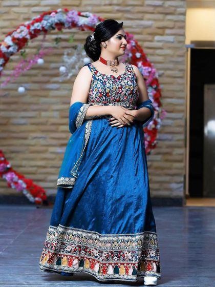 A client in a royal blue Anarkali-style lehenga with a multi-colored embroidered yoke. This is a classic and elegant choice for wedding guests.