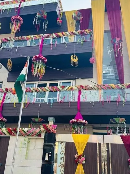 A grand house decoration with multiple layers of drapes, hanging floral baskets, and traditional ornaments. This creates a rich and festive look for a big celebration.