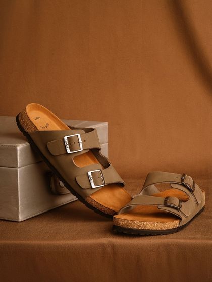 A clean, simple studio shot of two-strap sandals, focusing on the product's classic design and texture against a neutral background.