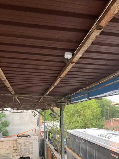 This camera is positioned to overlook a bus and other vehicles at a depot. It's crucial for monitoring vehicle safety and unauthorized access.