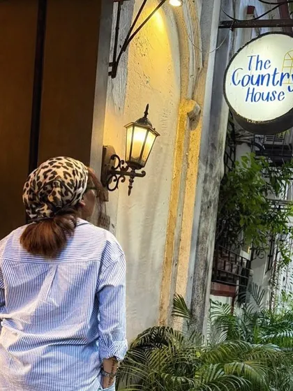 A candid shot outside a cozy cafe. The oversized striped shirt and leopard print bandana create a relaxed yet stylish look, perfect for a quiet coffee break.