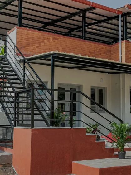 The L-shaped staircase is a key feature of the Anganwadi, combining a concrete base with sleek metal treads. It adds a unique scale to the building and provides access to the rooftop play area, turning a simple circulation element into a point of interest.
