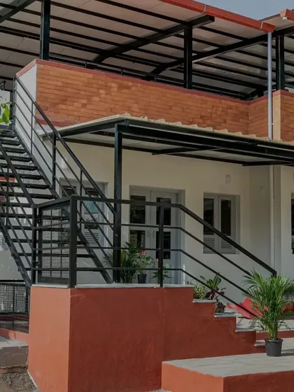 The L-shaped staircase is a key feature of the Anganwadi, combining a concrete base with sleek metal treads. It adds a unique scale to the building and provides access to the rooftop play area, turning a simple circulation element into a point of interest.