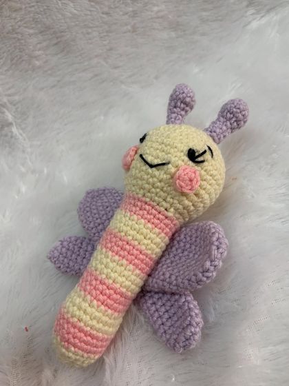 A view of the butterfly rattle with its eyes closed, giving it a sweet, sleepy expression. The wings and striped body provide great texture for tiny hands.