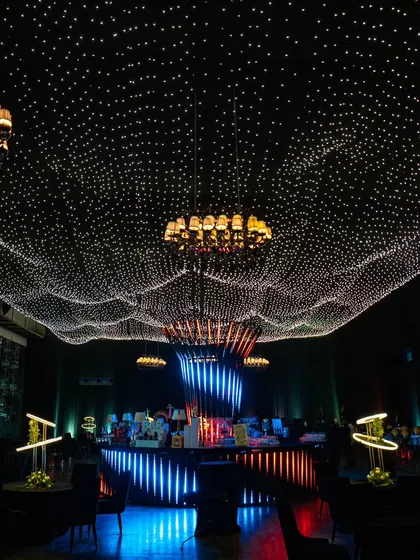 We transformed an indoor venue into a celestial dreamscape with a ceiling of countless fairy lights. This immersive lighting design, complemented by grand chandeliers, creates a magical 'sky full of stars' for a truly luxurious celebration.