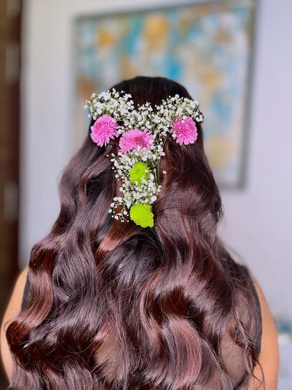 A half-up hairstyle with soft waves, adorned with fresh flowers. This is a versatile look that works for many different events.