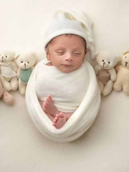 A wide view of the teddy bear lineup, with the sleeping newborn as the star of the show.