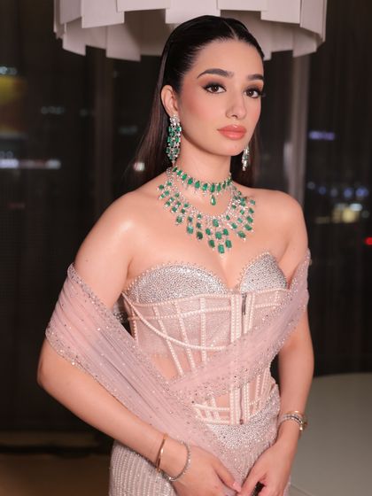 The intricate details of the corset and the delicate draping are the highlights of this look, complemented by soft, radiant makeup.