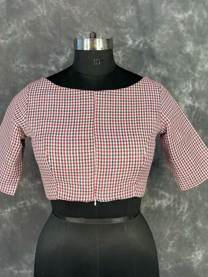 A front view of the classic checked cotton blouse on a mannequin. The front zipper is clearly visible, highlighting the modern touch on this traditional-style garment.