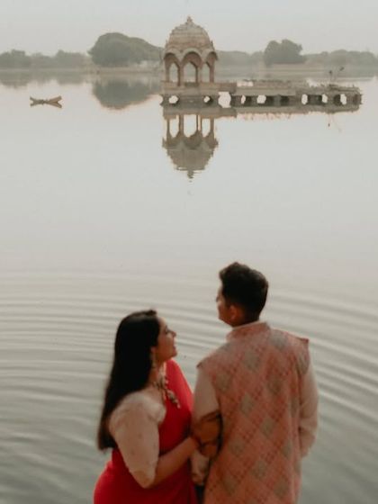 A serene moment by the tranquil waters of Gadisar Lake in Jaisalmer. The reflection in the water and the historic architecture in the background create a picturesque and romantic setting for this couple's portrait.