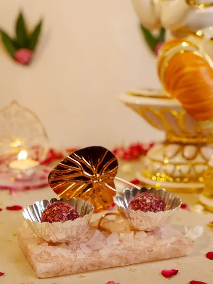 A festive offering to Lord Ganesha. This scene captures the spirit of celebration with modaks served in silver bowls on a rose quartz tray, creating a beautiful and devotional display.