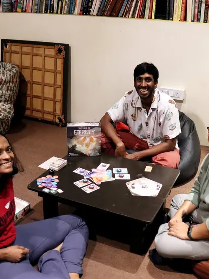 Three friends are all smiles while playing 'The Vale of Eternity' in our cozy library nook. The floor seating and bean bags create a relaxed, homely vibe for gaming.