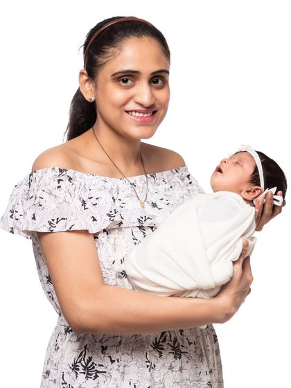 A simple and clean portrait of a mother holding her sleeping baby against a white studio background. This style emphasizes the peaceful bond between mother and child.
