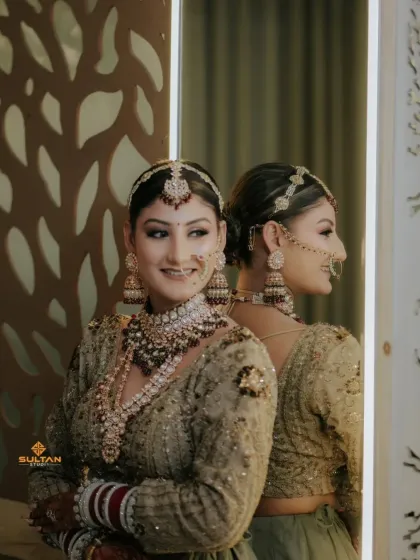 A stunning bride posing in front of a mirror on her wedding day. You can see the intricate mehendi on her hands.