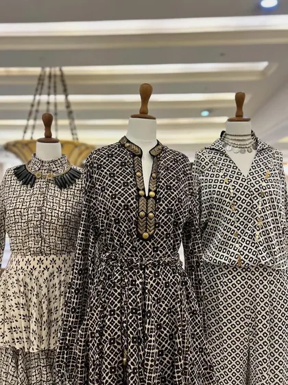 The full trio of black and white printed outfits, each accessorized with a unique statement necklace to complete the look.