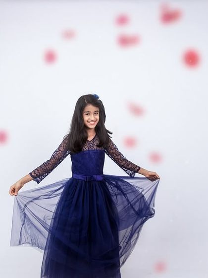 A magical studio portrait of a girl in a beautiful blue dress, with petals falling around her. This setup creates a dreamy, fairytale-like image.