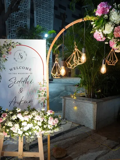 This welcome sign for Siddhi and Ankur features a modern arch design, accented with geometric lamps and soft florals, creating a chic and contemporary first impression.