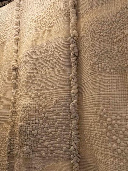 A detail of the highly textured, hand-stitched fabric from the 'Sleep Sense' installation. The running stitch and layered materials are reminiscent of traditional quilts, creating a comforting and dream-like experience.