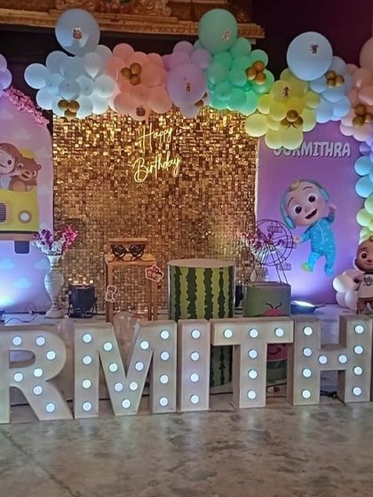 A Cocomelon party with a gold shimmer backdrop and large marquee letters, adding a touch of glam to the colorful theme.