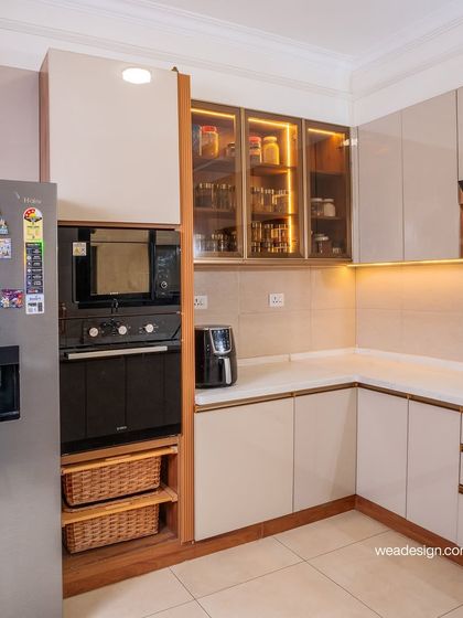 This kitchen combines acrylic cabinets with open wooden shelves and wicker baskets for a mix of modern and natural textures.