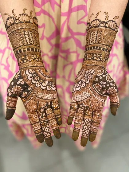 A beautiful semi-bridal mehandi with a mix of bold floral mandalas and delicate check patterns on the fingers and arms.