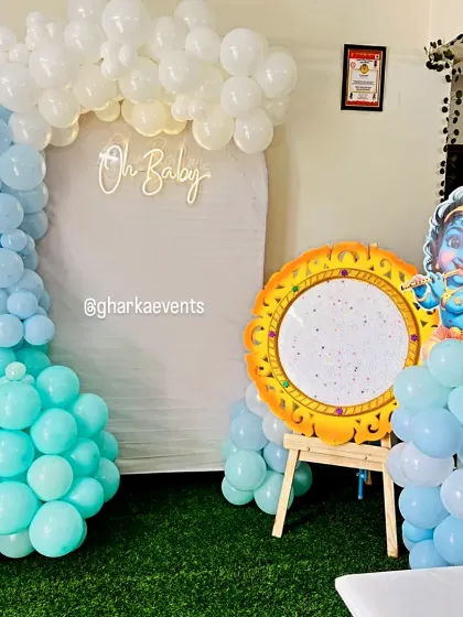 A unique baby shower or naming ceremony setup featuring a Little Krishna cutout. The blue and white balloon arch and "Oh Baby" neon sign create a sweet and spiritual theme.