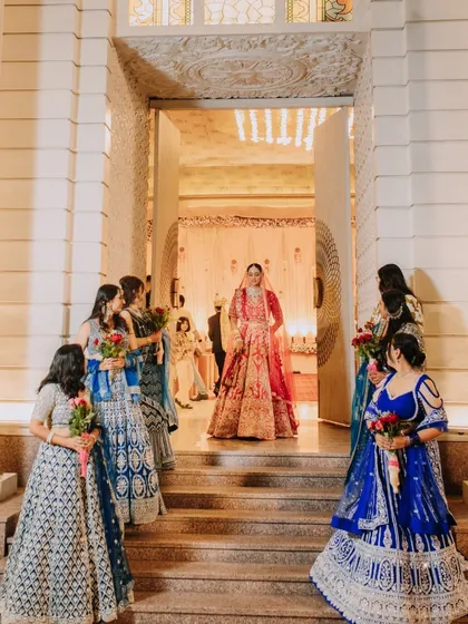 The bride makes her grand entrance, framed by the doorway and her bridesmaids, creating a moment of beautiful anticipation.
