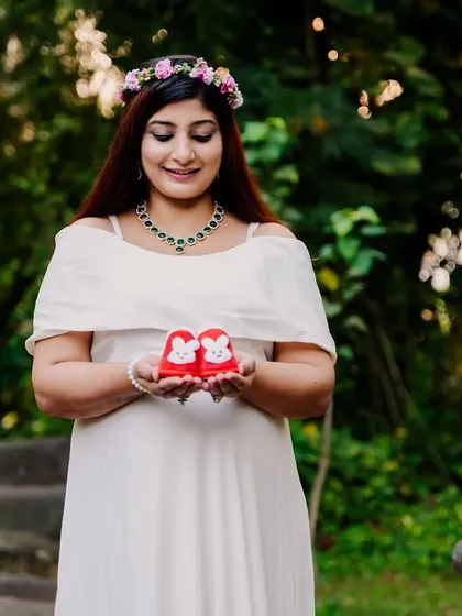 A sweet solo shot of the mom-to-be holding a pair of tiny red baby shoes, a symbol of the little life she's so excited to meet.