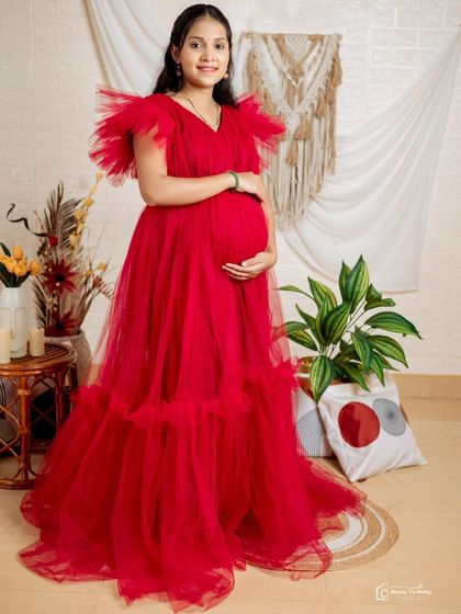 This vibrant red ruffled maternity gown is a fantastic choice for indoor studio shoots. The bold color and voluminous tulle on the shoulders and hem create a celebratory and joyful look.