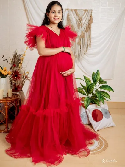 This vibrant red ruffled maternity gown is a fantastic choice for indoor studio shoots. The bold color and voluminous tulle on the shoulders and hem create a celebratory and joyful look.
