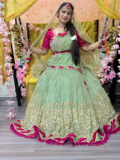 A happy client looking radiant in a green and pink lehenga for her godh bharai (baby shower) ceremony, which has a similar vibe to Mehendi.