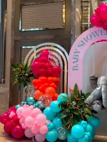 A section of the vibrant elephant-themed baby shower, showing the bold color combination of pink, red, orange, and teal balloons.