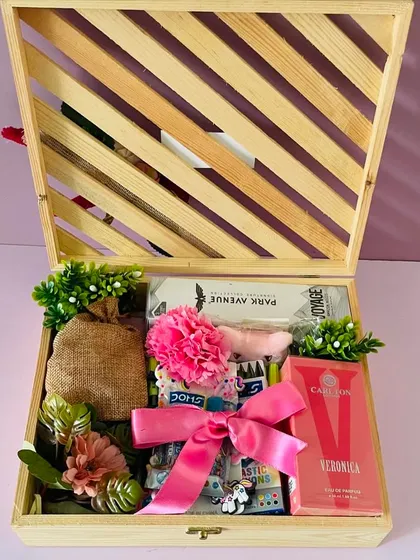 Inside the Rakhi wooden box, a collection of gifts for the whole family, including perfumes and treats, tied with a pink ribbon.