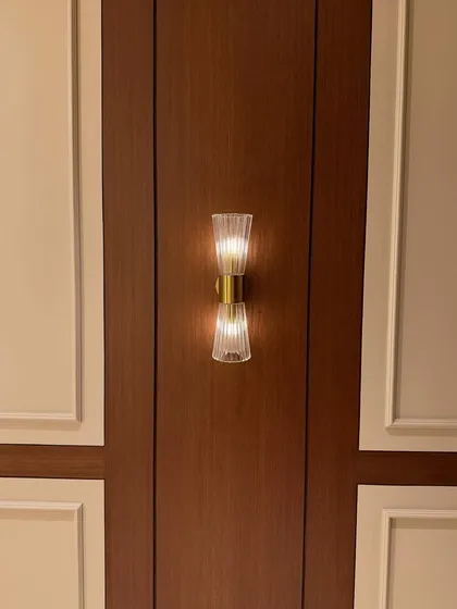 A close-up of a classic wall sconce set against dark wood and light-colored paneling. This kind of accent lighting adds a layer of sophistication to the entrance area.