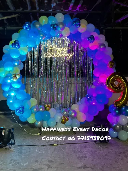 A balloon ring decoration for a 9th birthday party on a terrace. The setup is lit with spotlights and features a large foil '9' balloon.
