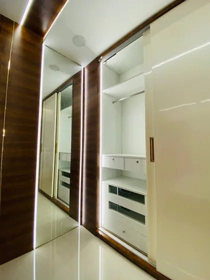 A look at the sliding wardrobe with one door open. The mirrored panel on the other door helps make the walkway feel more spacious, while the profile lighting adds a touch of luxury.