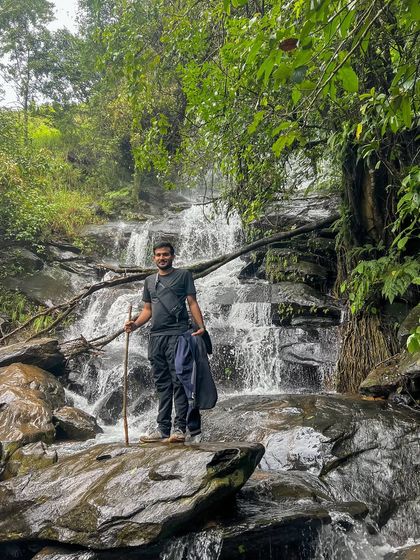 A trekker pauses by a beautiful cascading waterfall, a common and refreshing sight on the Netravathi trail.