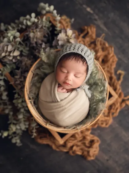 A classic, posed newborn portrait. I am trained in newborn safety to achieve these peaceful, curled-up poses. This shot highlights the baby's delicate features in a rustic, earthy setup.