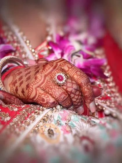 A close-up of the bride's hand, showcasing her beautiful mehndi and the stunning engagement ring. This shot highlights the important symbols of commitment and tradition.