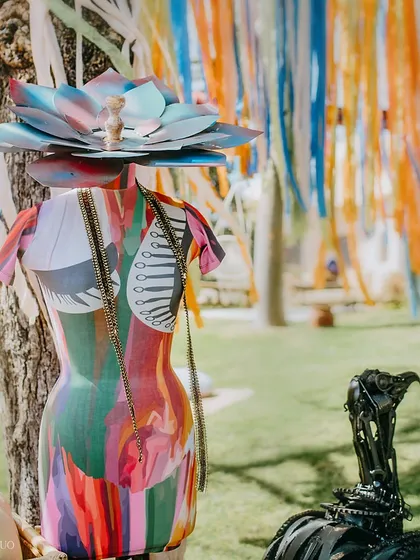 A painted mannequin torso, adorned with a lotus headpiece and chains, stands by a tree, contributing to the eclectic and artistic vibe of the event.
