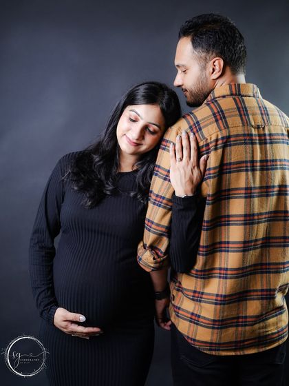 A modern and moody couple's portrait. The mom-to-be rests her head on her partner's shoulder, showing trust and intimacy.